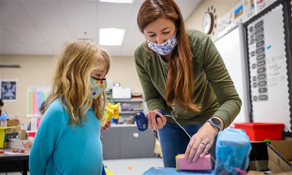Teacher helps student build recycled material castle